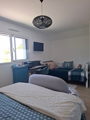 A bedroom with a bed, a desk, a chair, a wardrobe, and a hanging light fixture. - Guesthouse 'Paloma à la Mer' 150m from the beach with terrace, garden and Wi-Fi (Pornichet)