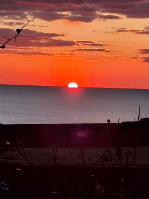 A sunset over a body of water with a horizon line.