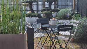 A patio with a table and chairs, surrounded by potted plants and a wooden fence. - Paloma by the Sea Guest Room with Shared Terrace, Garden, and Wi-Fi (Pornichet)