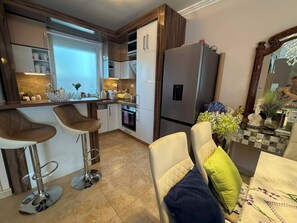 Eine moderne Küche mit Kühlschrank, Backofen und Barhocker.