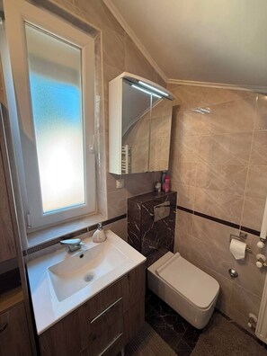Ein modernes Badezimmer mit Waschtisch, Spüle, Spiegel und Toilette.