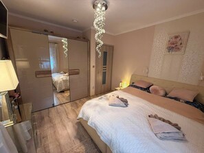 Une chambre d’hôtel avec un lit, des lampes de chevet, un miroir et un tableau au mur.