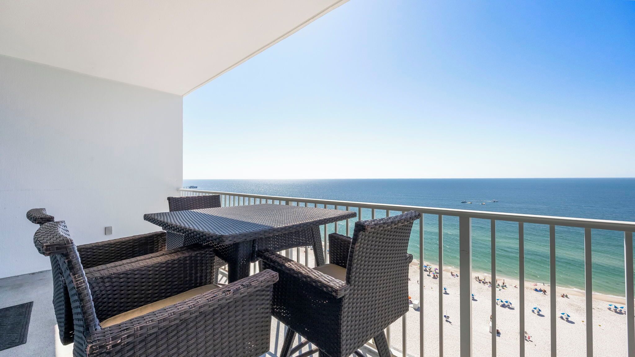 Ein Balkon mit Korbmöbeln, der Blick auf einen Strand bietet.