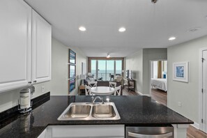 Una cocina moderna con un lavamanos doble, una zona de comedor con mesa y sillas, y vista al océano.
