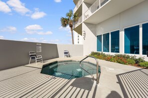 A swimming pool with a metal ladder, lounge chairs, a palm tree, and a building with large windows. - Lighthouse 1414 - Owner Managed, Fully Updated. Beautiful 3BR Gulf Front Condo. (Gulf Shores)