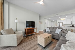 A modern living room with a flat-screen TV, two sofas, a coffee table, and a floor lamp. - Lighthouse 1414 - Owner Managed, Fully Updated. Beautiful 3BR Gulf Front Condo. (Gulf Shores)