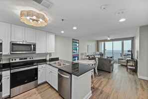 Una cocina moderna con electrodomésticos de acero inoxidable, una encimera negra y un comedor con vistas.