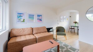 A living room with a sofa, a chair, a small table, and artwork on the wall. - Stylish Brunswick Retreat Free Parking Near CBD (Brunswick)