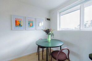 A room with a round table, two chairs, and a window. There are three framed pictures on the wall. - Stylish Brunswick Retreat w Free Parking Near City (Brunswick)
