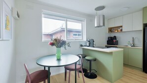 A modern kitchen with a dining area, a window, and a view of the outside. - Stylish Brunswick Retreat Free Parking Near CBD (Brunswick)
