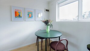A room with a round table, two chairs, and a window. There are three framed pictures on the wall. - Stylish Brunswick Retreat Free Parking Near CBD (Brunswick)