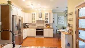 A kitchen with white cabinets, stainless steel appliances, and a wooden floor. - The Cowboy Capital Escape: Resort-Style Backyard Pool & Outdoor Living. (Bandera)