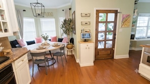 A kitchen with a dining area, wooden flooring, white cabinetry, a large window with blinds, and a door with glass panels. - The Cowboy Capital Escape: Resort-Style Backyard Pool & Outdoor Living. (Bandera)