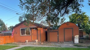 A small, single-story house with a front porch, a garage, and a fenced yard. - Le Maison Bruin  (Cortez)