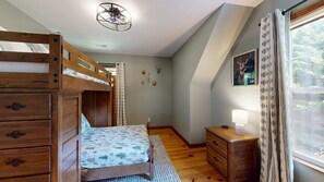 A bedroom with a bunk bed, a bedside table with a lamp, a wall-mounted heater, and a window with curtains. - Great for gatherings, hot tub, sauna, gas grill, firepit, gameroom, outdoor seating (Leicester)