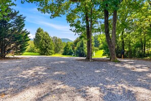A gravel parking area with trees and a distant view of a mountain. - Great for gatherings, hot tub, sauna, gas grill, firepit, gameroom, outdoor seating (Leicester)
