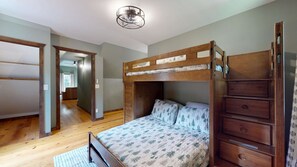 A bunk bed with a wooden frame, a lower bed with a patterned quilt, and a wooden dresser with drawers. - Great for gatherings, hot tub, sauna, gas grill, firepit, gameroom, outdoor seating (Leicester)