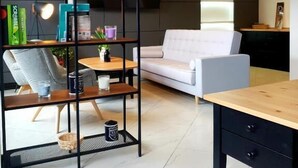 Una sala de estar moderna con un sofá, una mesa de centro, una estantería e iluminación colgante.