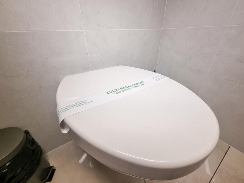 Un inodoro blanco con una etiqueta en un baño con paredes de azulejos.