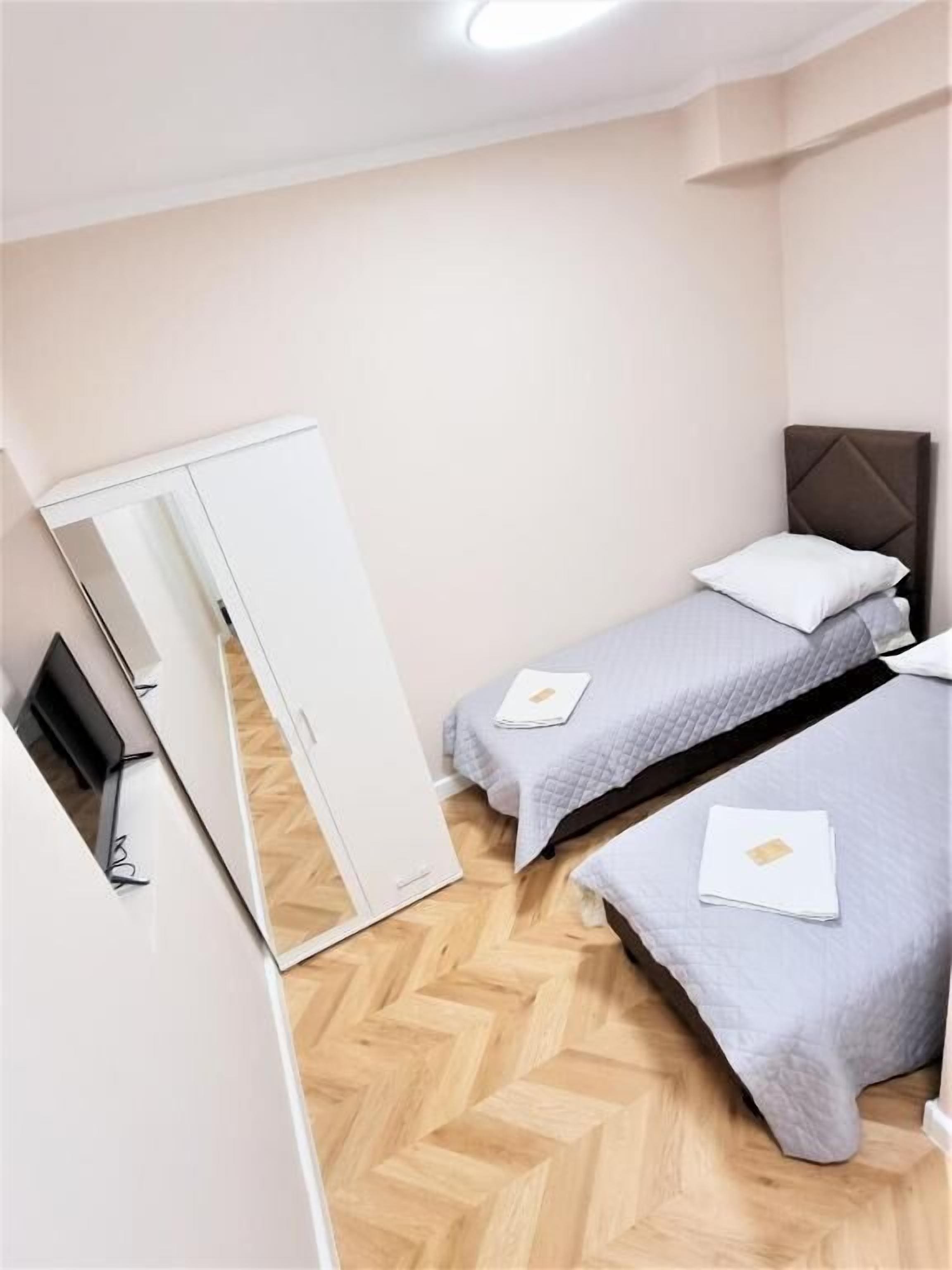 Un dormitorio con dos camas individuales, un armario y un espejo.