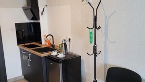 Una cocina compacta con horno integrado, un refrigerador pequeño y una silla.