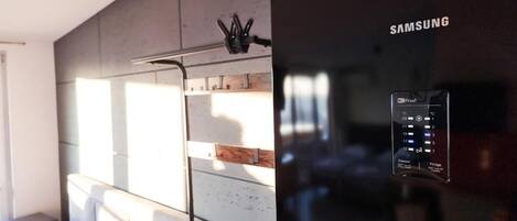A modern bedroom with a built-in Samsung refrigerator, a bedside table, and a headboard.
