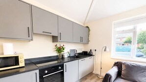Een moderne keuken met grijze kastjes, een zwart aanrecht en een ingebouwde oven.