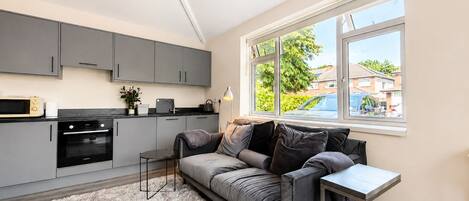 A modern kitchen with grey cabinets, a black oven, and a small table.