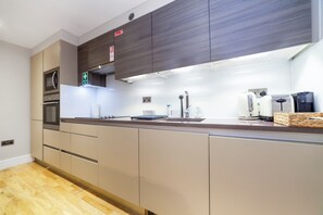 A modern kitchen with built-in appliances, a first aid box, and a clean, minimalist design. - Host My Nest - Modern 2 Bed Apartment by Hyde Park (London)