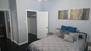 Ein Schlafzimmer mit Bett, Nachttischen, einem Kleiderschrank und einer Tür.