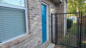 A brick house with a blue door, a black metal gate, and a window with blinds. - 2BR/2BA Sleeps 6, 15 min walk to AT&T Stadium & Entertainment District (Arlington)