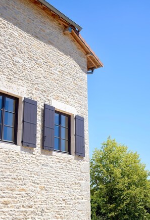Un edificio de piedra con tres ventanas y un borde de techo de madera.