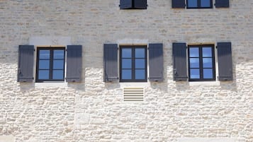 A two-story building with a stone facade and multiple windows with shutters.
