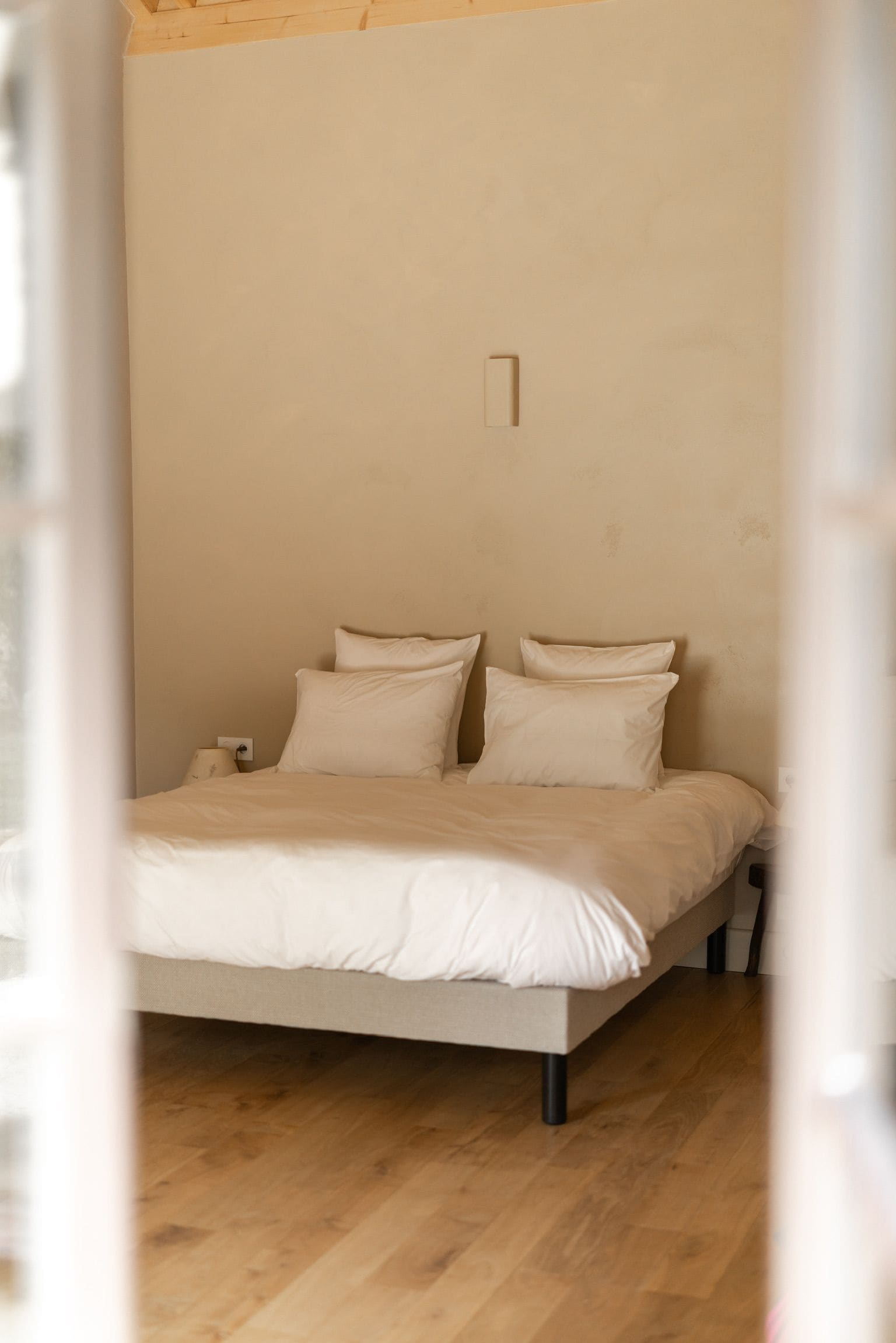 Un dormitorio con cama, almohadas y mesita de noche.