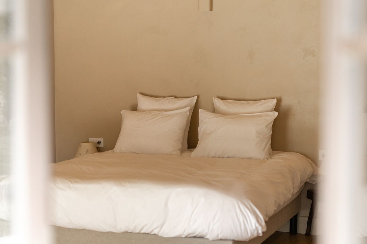 A bedroom with a bed, pillows, and a nightstand.