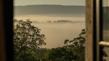 Uitzicht door een raam, met een heldere lucht, een verafgelegen bergketen en een laag mist of nevel.