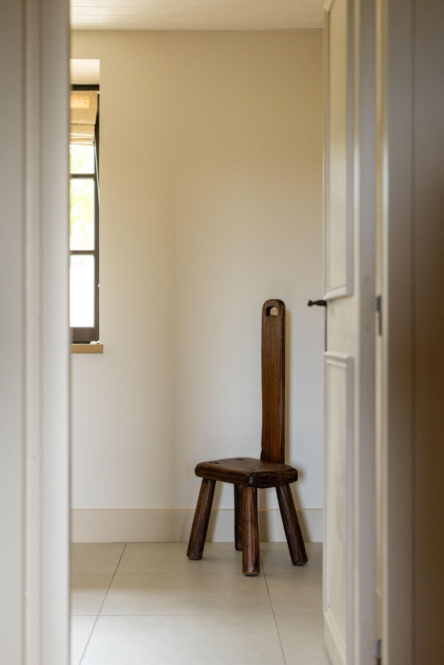 Un pasillo con una silla de madera y una ventana.