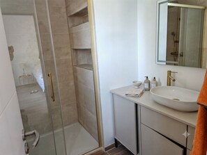 A modern bathroom with a glass shower enclosure, a white sink with a gold faucet, and a mirror above the sink. - House nestled among the pine trees between Cadenet and Lourmarin, with a pool (Cadenet)