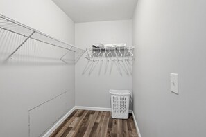 A laundry room with a metal drying rack, a white laundry basket, and a wall-mounted towel rack.