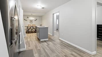 Een moderne keuken met een inbouwkoelkast, een klein eiland en een eethoek met tafel en stoelen.