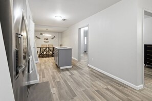 A modern kitchen with a built-in refrigerator, a small island, and a dining area with a table and chairs.