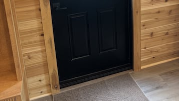 Eine schwarze Tür mit Fenster, die auf eine Terrass mit Stühlen und Tisch führt.