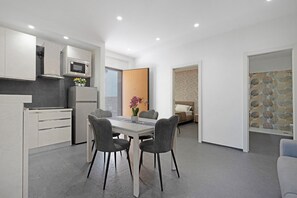 Une cuisine moderne avec un coin repas, un réfrigérateur, un four à micro-ondes et une table à manger avec des chaises.
