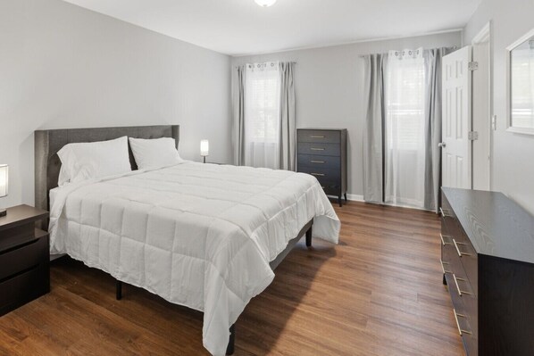 A bedroom with a bed, a dresser, a nightstand, and a wardrobe.