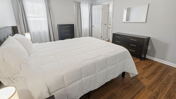 Une chambre à coucher avec un grand lit, une commode, un miroir et une porte.