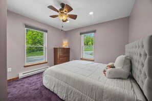 Une chambre à coucher comprenant un lit, une table de chevet, une commode et un ventilateur de plafond.