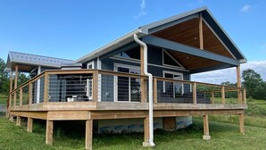 Et moderne hus med to etager, en træterrasse, store vinduer og et skråt tag.