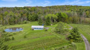 Une propriété rurale comprenant une maison, un étang et une colline boisée.