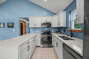 Une cuisine moderne avec des armoires blanches, des appareils en acier inoxydable et un mur d’accent bleu.