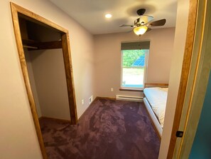 A bedroom with a bed, a ceiling fan, a window, and a door.